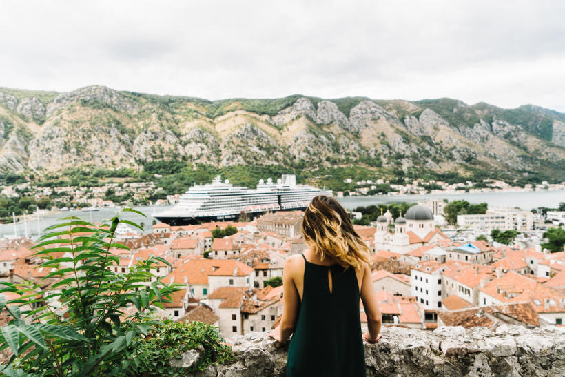girl on hill overlooking european town with ship in harbour