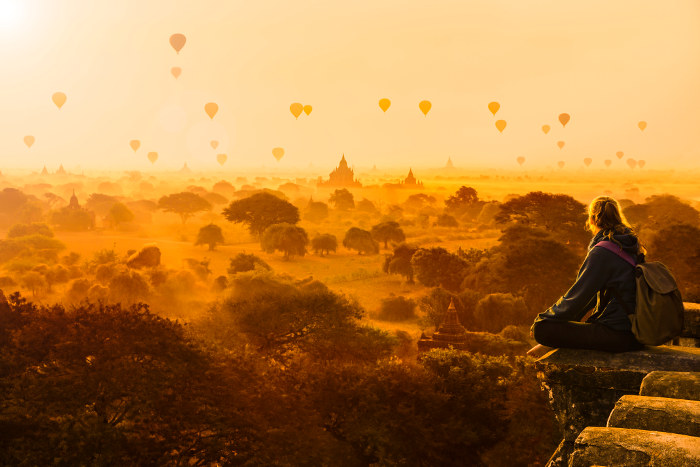 girl on temple overlooking balloons and temples at sunrise myanmar