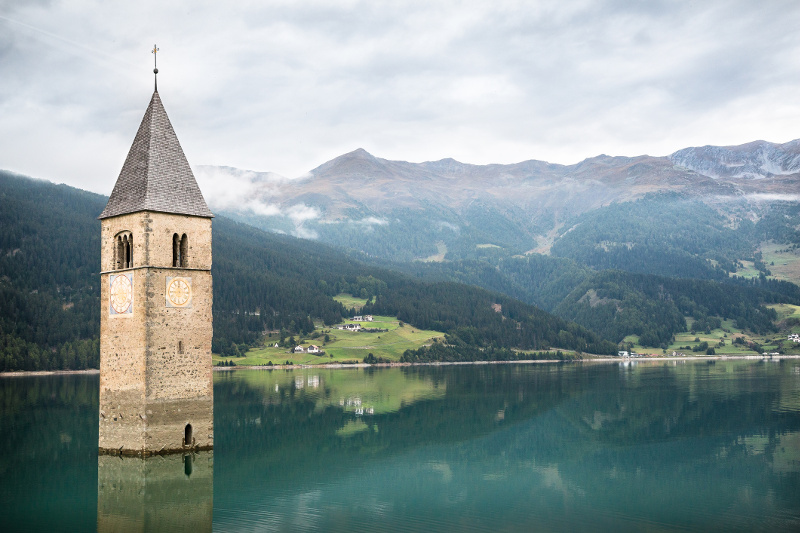 bell tower jutting out of lake