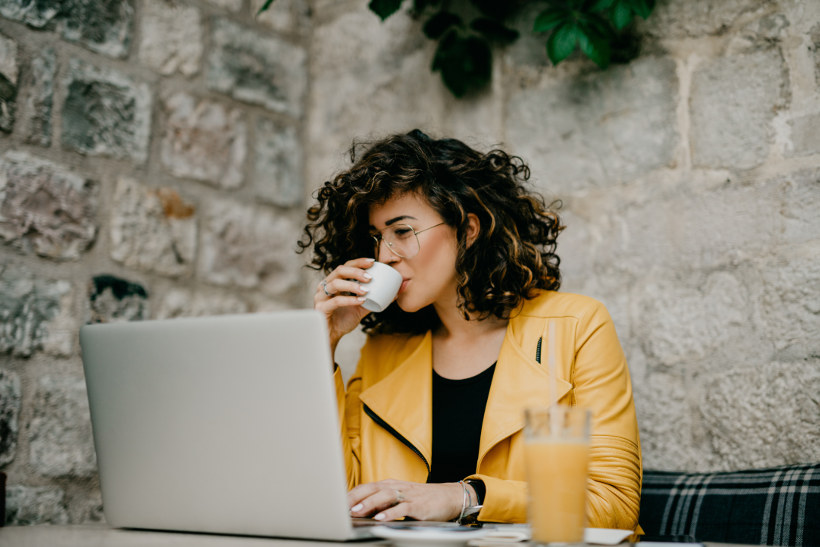 woman working on computer drinking coffee