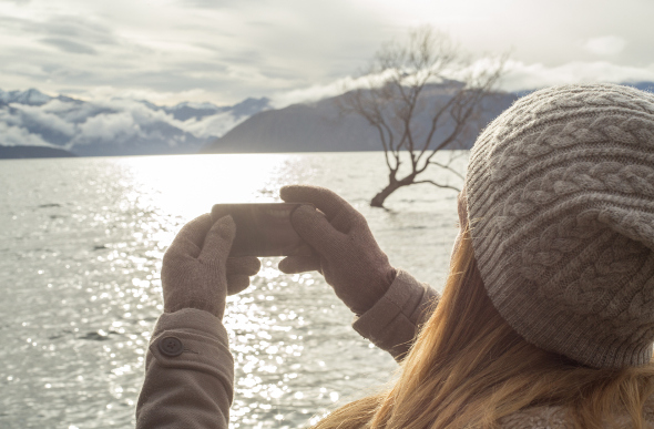 A girl taking photos wearing gloves and a hat