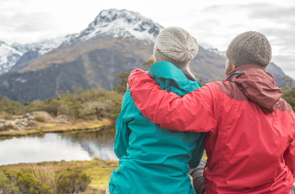 Two people looking at the mountain while wearing hats