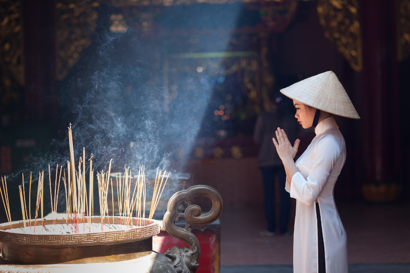 Local woman at temple with incense in Ho Chi Minh City, Vietnam.