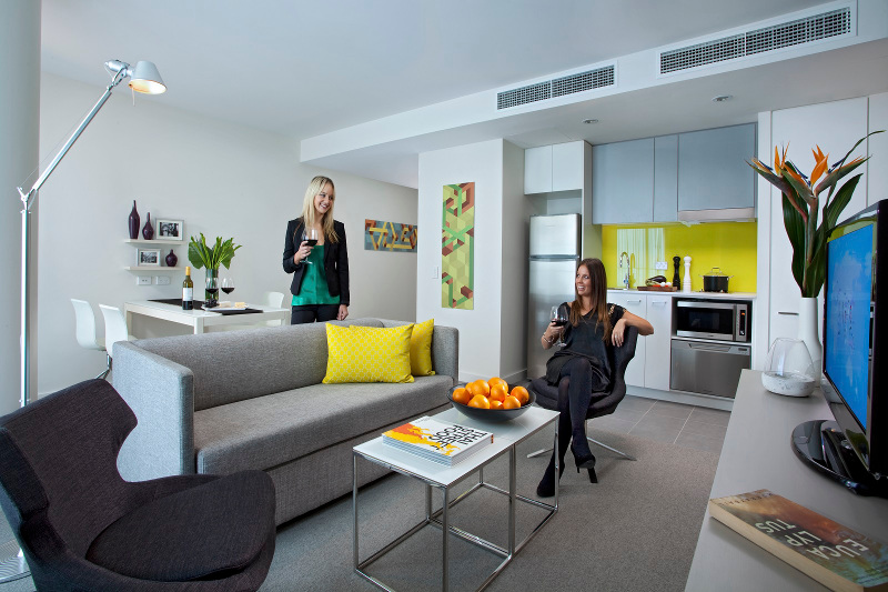 Two women relax with a glass of wine in an apartment at the Citadines on Bourke hotel in Melbourne, Victoria.