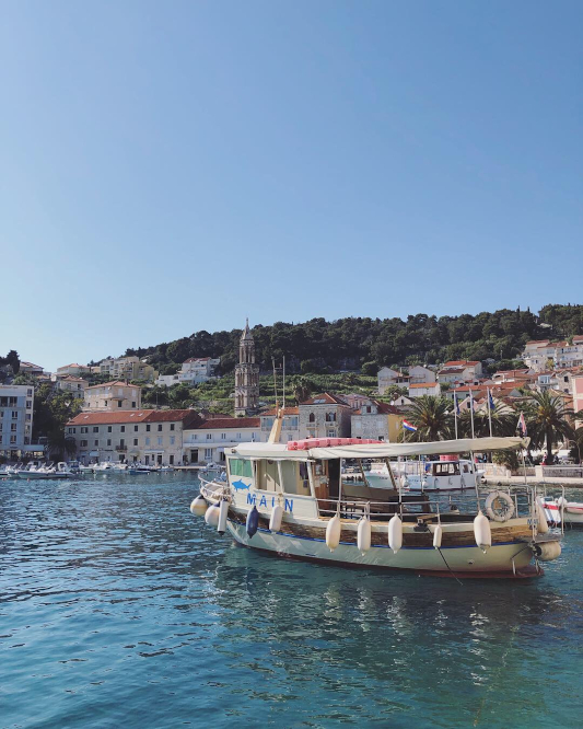 Boat that is anchored with hvar old town in the background