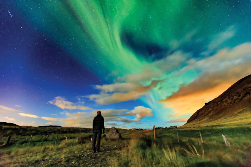 girl beneath northern lights iceland