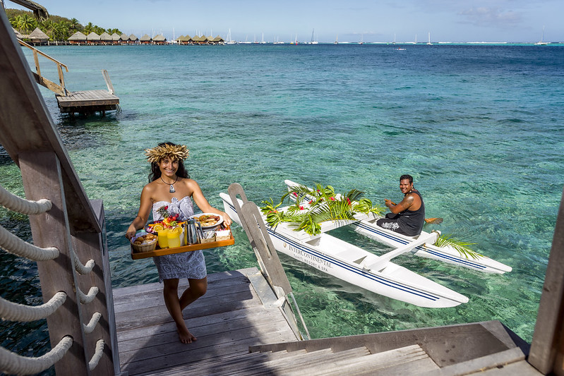 Photo of two locals bringing room service to the overwater bungalow 