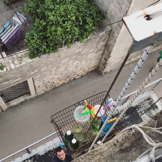 A man below using pulley system to transport cocktails to the top of a tower. The colourful cocktails are almost at the top