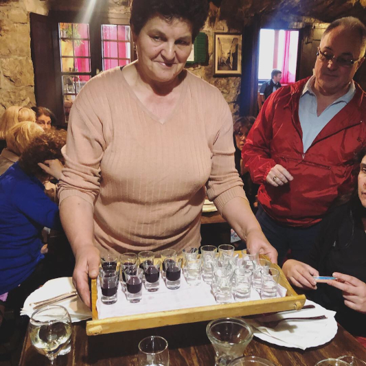 A local woman serves local liqueur on a tray