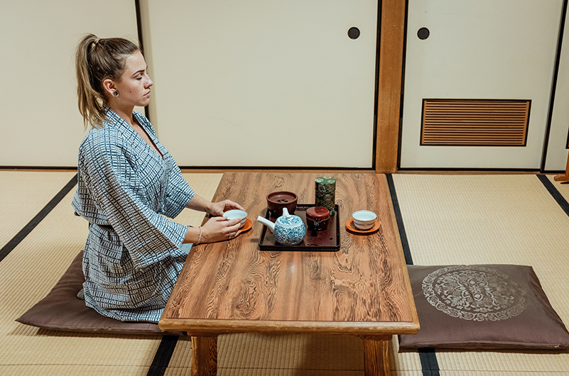 A woman sits within a Japanese temple stay room