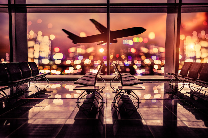 A plane takes off with city lights glowing golden in the background.