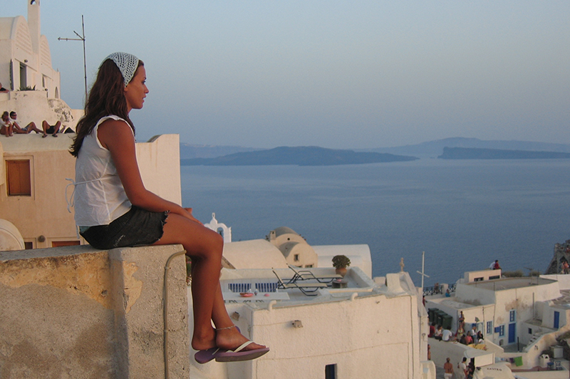 A woman watches the sun set in Oia, Santorini.