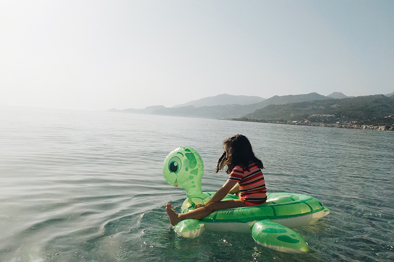 A young girl in an inflatable pool toy swims in the Mediterranean Sea.