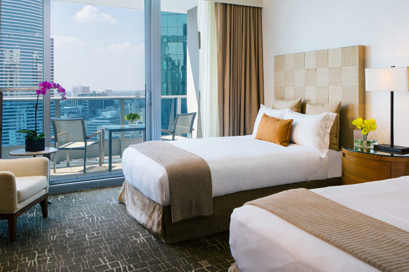 A guestroom at the Kimpton EPIC Miami, with a view out to the balcony and the CBD.