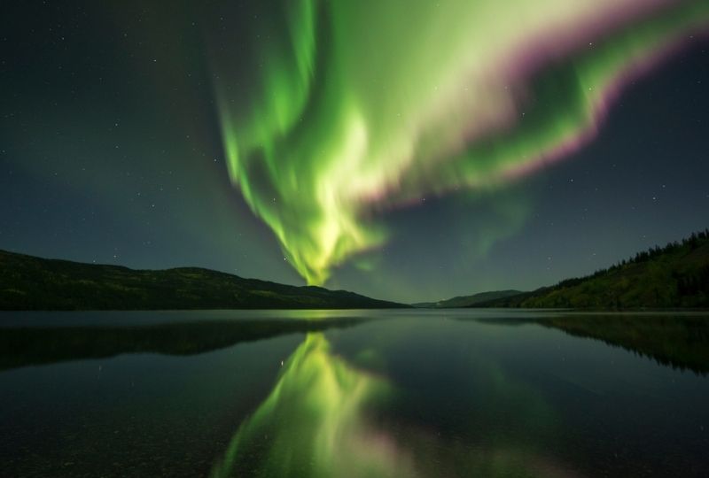 Image of northern lights reflecting onto lake in Yukon