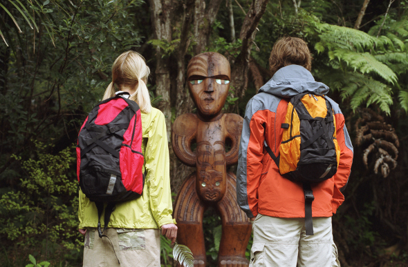 A couple standing in front of a Maori carving