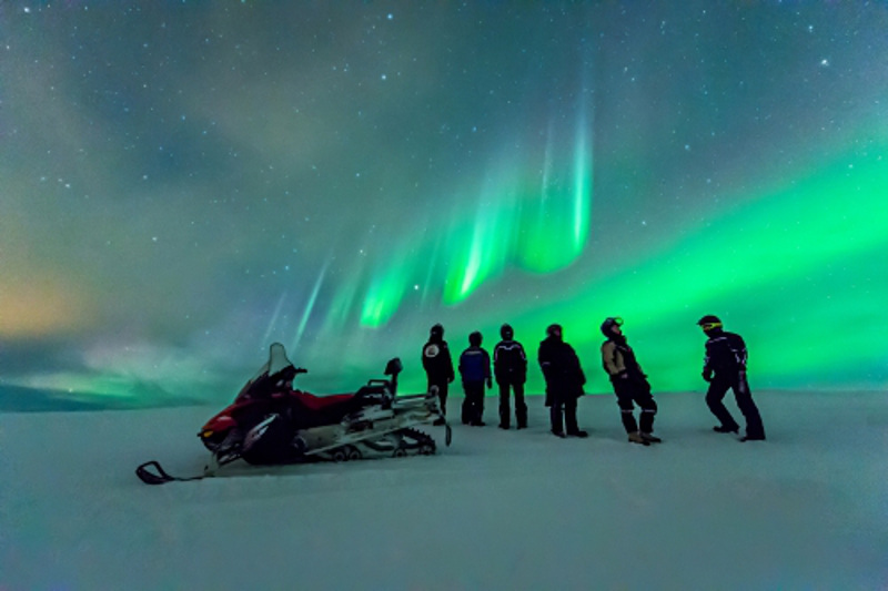 snowmobiles under northern lights Finland