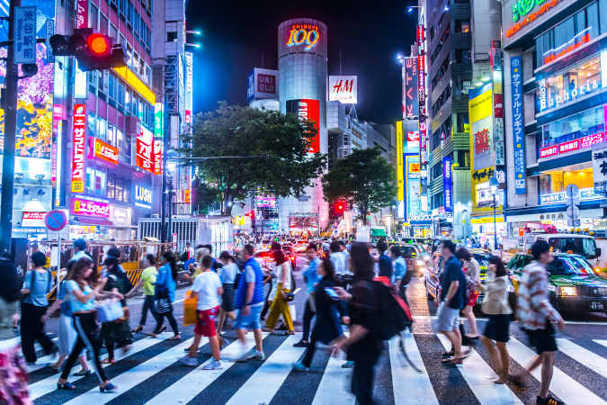 a busy crossing in tokyo with lots of lights and colours from the ads