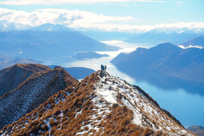 a family standing on a mountain top with a lake and other mountains in the background