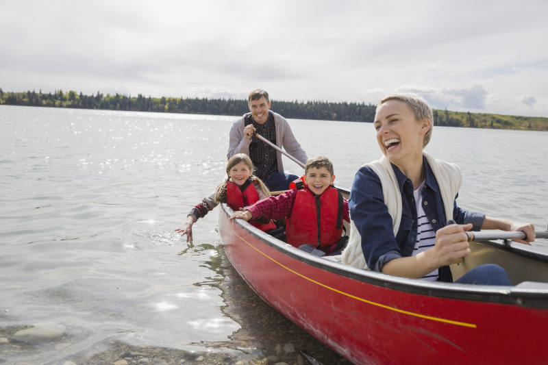family in a canoe on a lake laughing