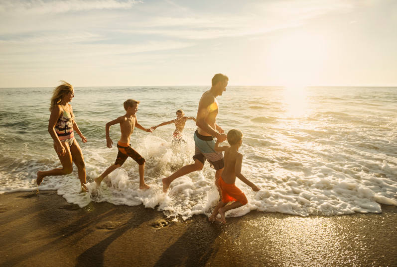 family running along the beach at sunrise