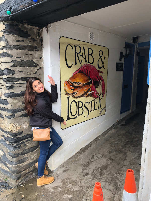 Sheridan standing next to a sign advertising the Crab and Lobster. 