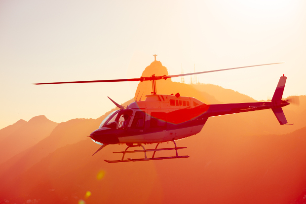A helicopter flies around the Christ the Redeemer statue in Rio de Janeiro, Brazil, at sunset.