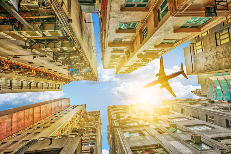 A plane flies above tall buildings in Hong Kong.