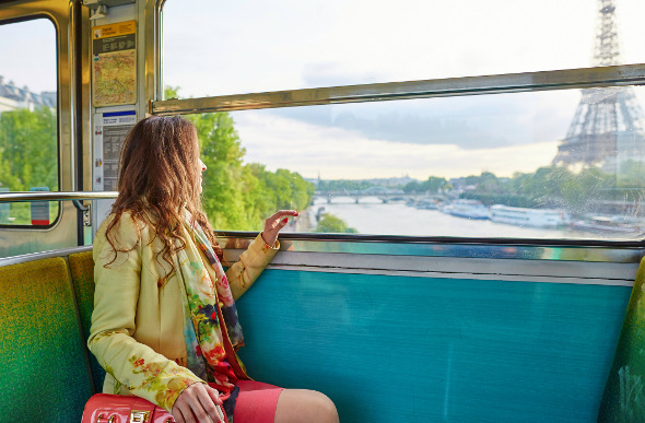 A woman stares at the Eiffel Tower through a train window.