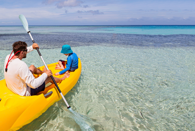 A man and boy in a kayak in shallow waters off Fiji's Coral Coast