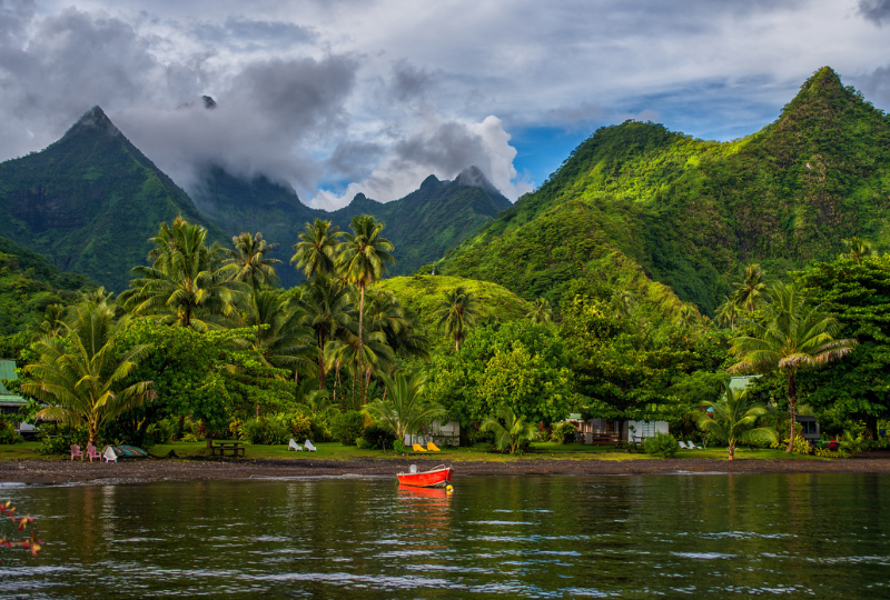 Mountain peaks pierce the clouds above the glassy waters of Teahupo'o