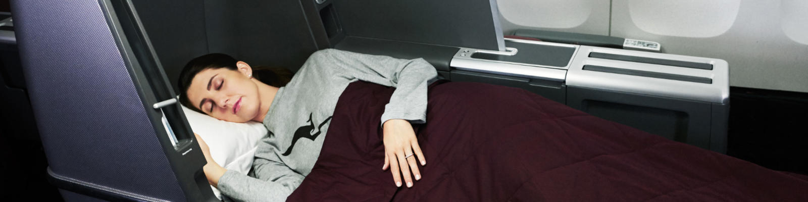 A woman sleeping on her Qantas Business Class lay flat seat