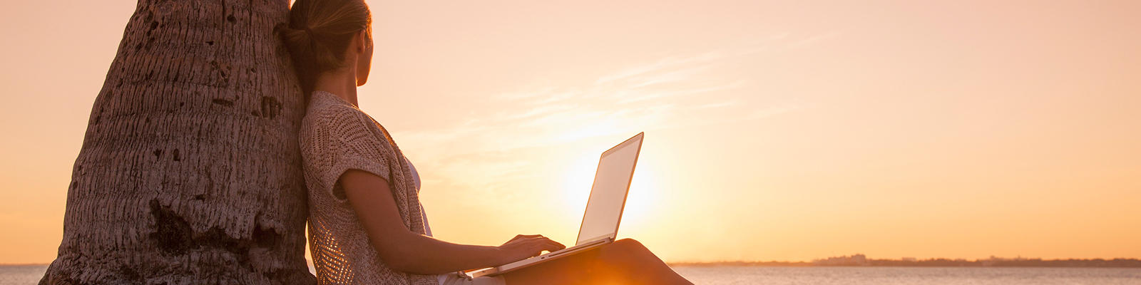 Working on a laptop during a beach sunset