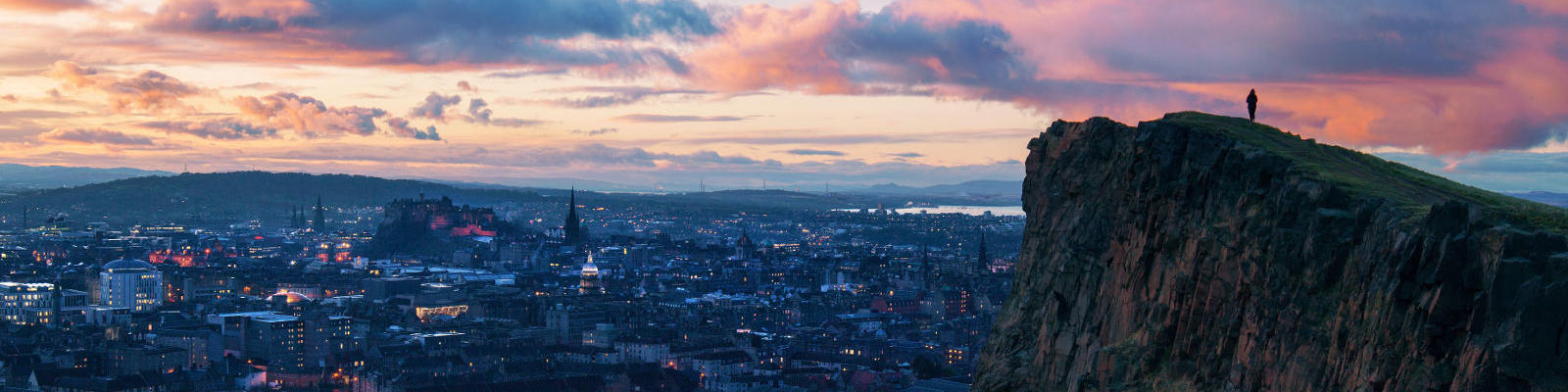 man on mountain over edinburgh sunset