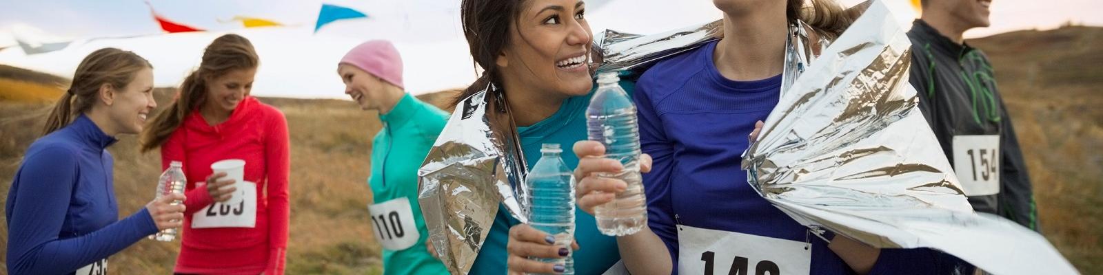 Smiling runners drinking water after marathon