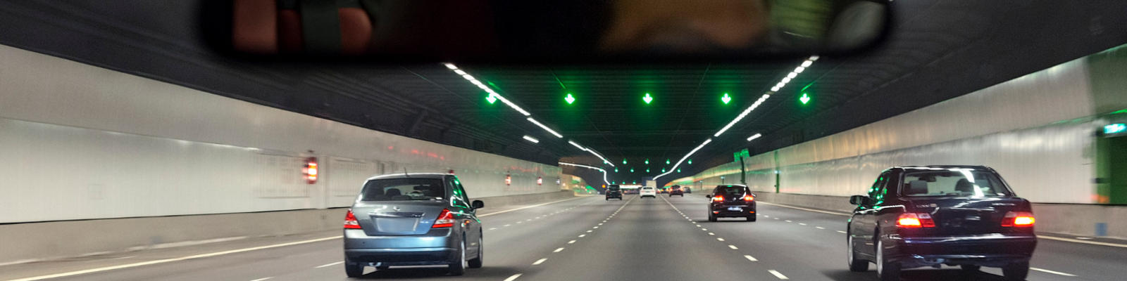 A view of cars driving through a tunnel from the point of view of a driver of the car at the rear