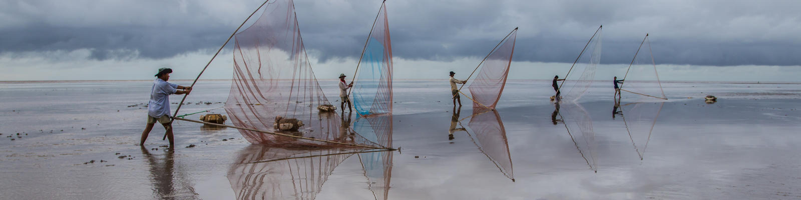 Fisherfolk cast their nets on a beach at the Mekong Delta in south Vietnam
