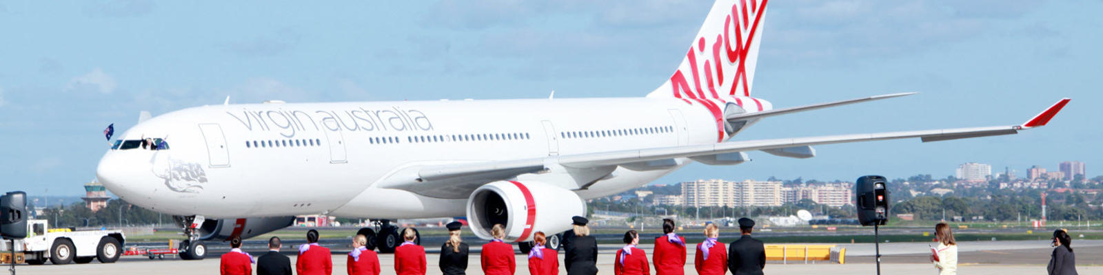 Virgin crew members standing on a red carpet looking at one of Virgin Australia's planes