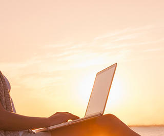 Working on a laptop during a beach sunset