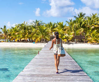 woman walking on boardwalk to tropical island