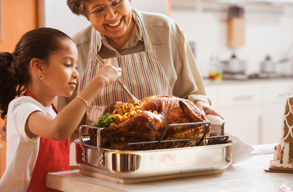 A grandmother and granddaughter cooking a Thanksgiving turkey