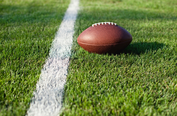 A football sitting on a football field yard line