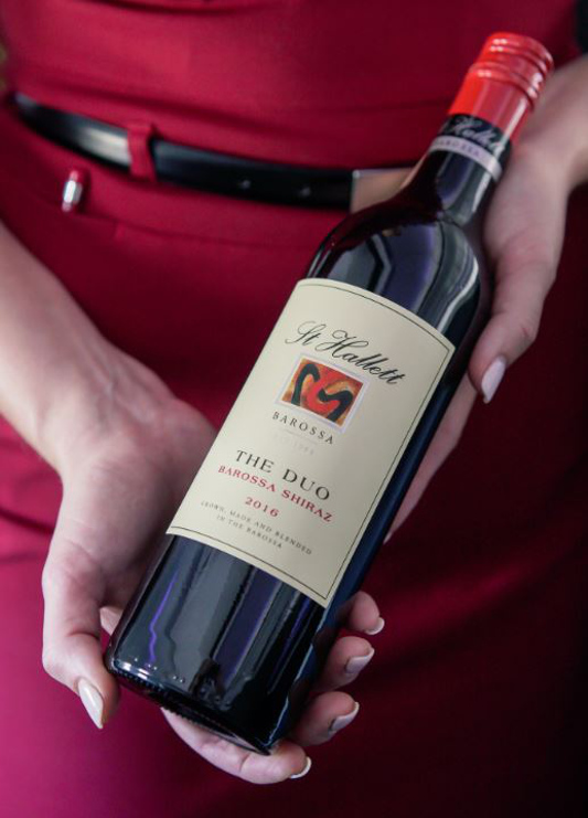 A Virgin Australia flight attendant holding a bottle of wine