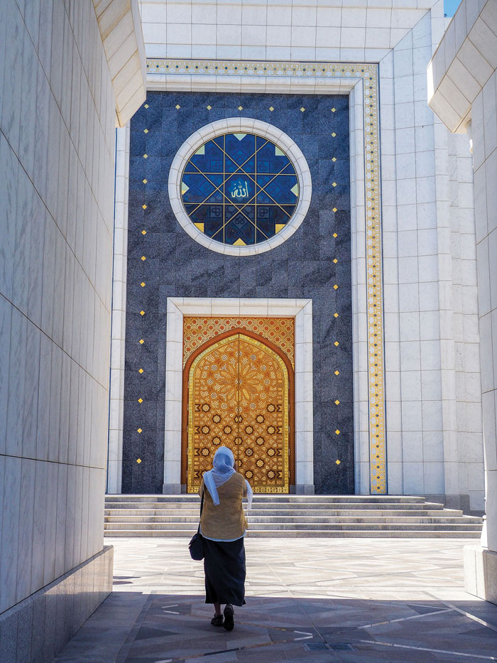 a woman walks to the door of Turkmenbashi Ruhy Mosque