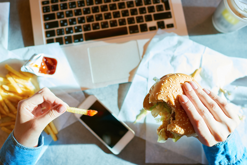 A woman eating a burger and fries while working