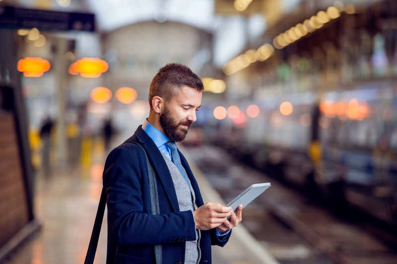 A man looking at a tablet at a train station