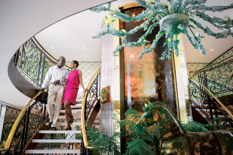 couple walking down staircase with atrium on uniworld ship