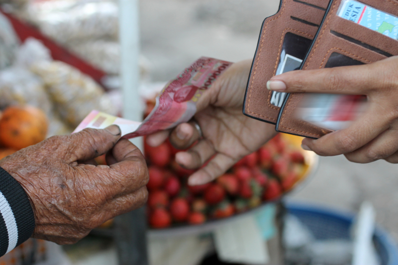 open wallet with a hand passing cash into another hand