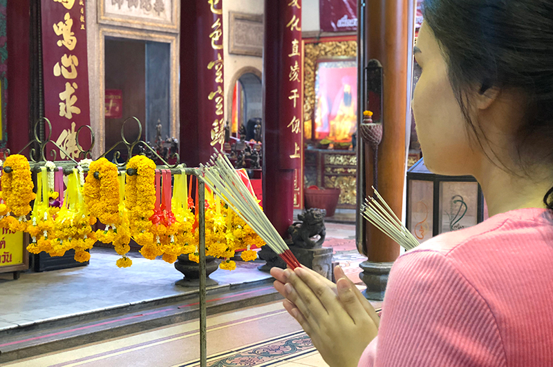 A woman offers incense at Wat Mangkon Kamalawat, Bangkok