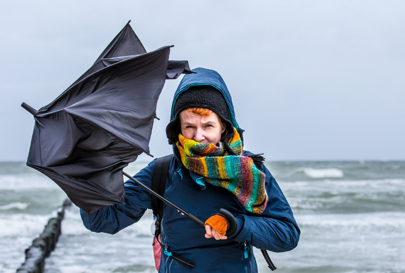 Women with broken brollie by a cold and raging sea